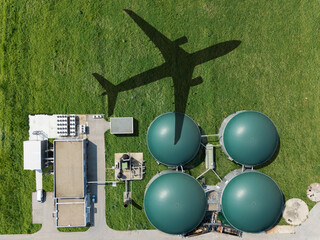An airplane flies over a biogas plant. A symbol of decarbonization and carbon neutrality in transport.