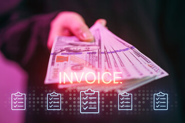 Person holds cash while looking at an invoice in a setting with dim lighting and colorful background © yurakrasil