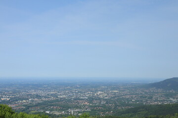 Fototapeta premium Panoramic view of city and countryside from mountain viewpoint under clear blue sky