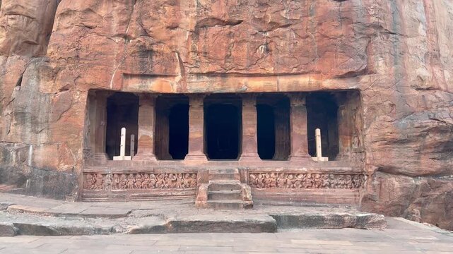 A majestic front and top view of Badami Cave Temple No. 2, showing the massive cliff-carved facade, sturdy stone pillars, and the towering red sandstone hill sculpted by the Early Chalukyan artisans.