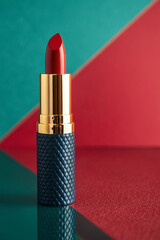 Vibrant red lipstick with luxurious gold and navy textured casing on a striking bi-color background