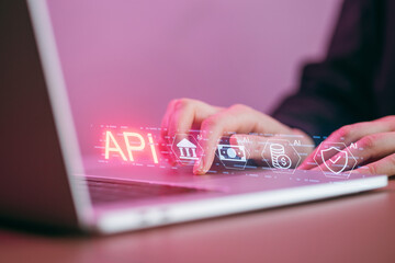 Hands work on laptop showing API interface with graphics in a workspace during afternoon hours