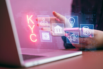 Digital display shows KYC process with icons and a woman using a laptop in a modern office setting
