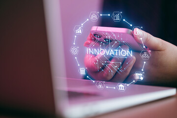 Hands holding a smartphone with innovation symbols and a laptop in the background