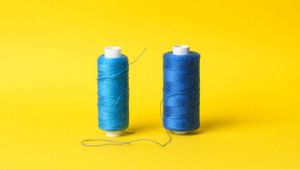 Two spools with blue thread on yellow background