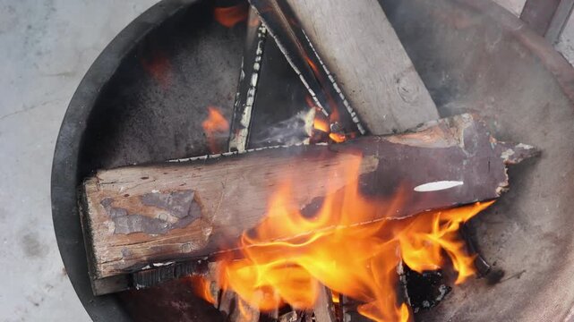 Wood burns with bright flames, showing warmth, heat, and traditional fire use during cold winter conditions in a simple rural Indian environment.