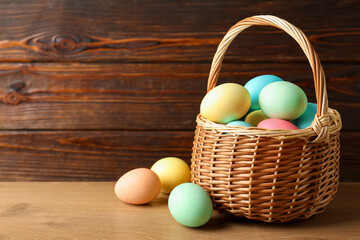 Beautiful Easter eggs in basket on wooden table. Space for text
