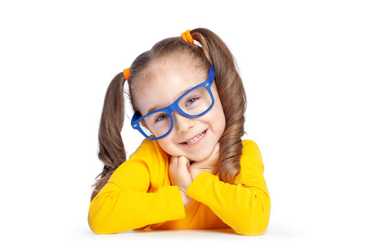 A cheerful child with curly pigtails and glasses leaning on her hands against a white background