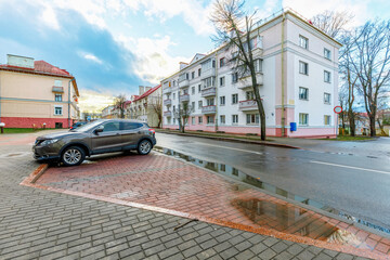 Dark SUV parked on a paved lot near urban residential houses