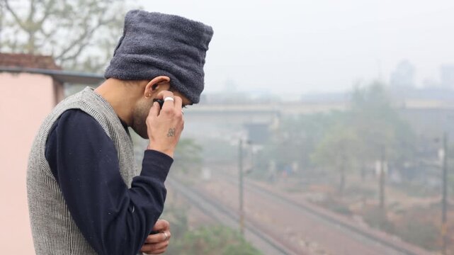 A man wears an earpod during a cold winter morning in Delhi, showing modern communication, technology use, and everyday urban lifestyle in winter conditions.