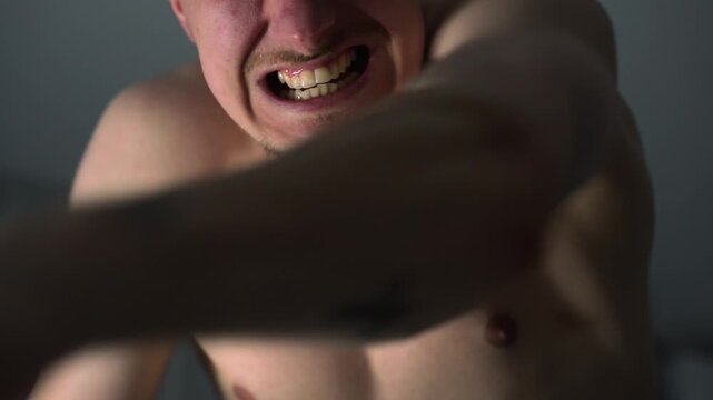 An angry man with a bare chest is fighting and punching someone.
A man is boxing with his hands.
Aggression and bullying