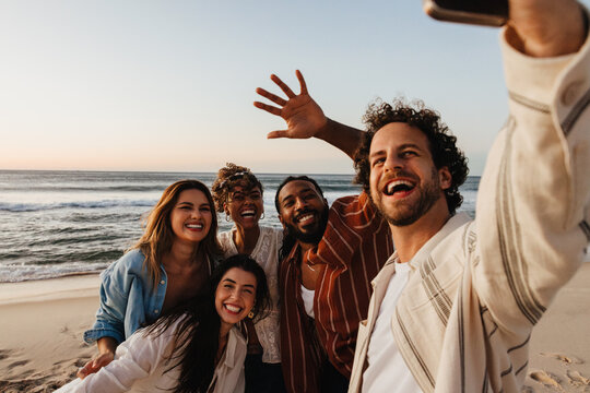 Group of friends taking a selfie at a beach during sunset