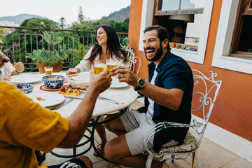 Group of friends having a joyful outdoor meal with drinks and appetizers