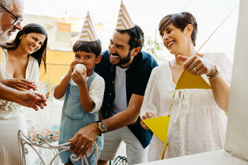 Family with party hats enjoying a birthday celebration outdoors