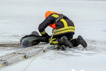 Obraz premium Firefighter rescues person from icy water during winter emergency response operation near frozen lake