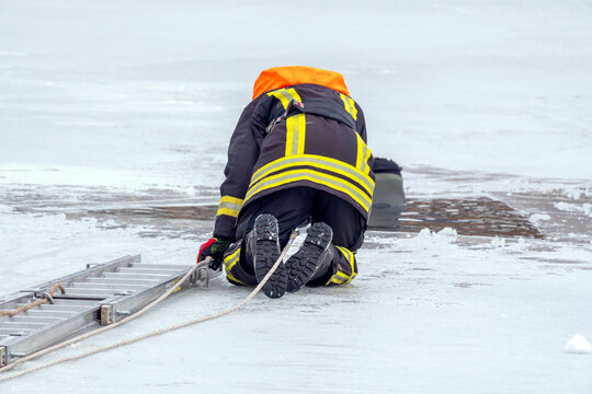Firefighter performs rescue operation on icy water surface in winter