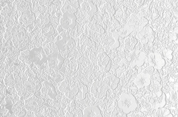 An intricate floral relief pattern adorns a textured grey-silver surface.