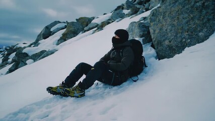 Backpacker resting on snowy mountain slope, 4k clip