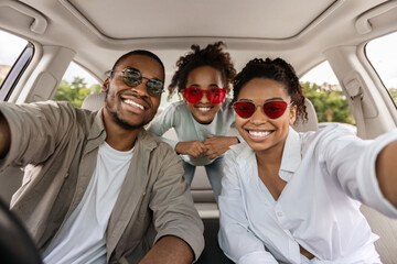 Cheerful African American Family Of Three Posing In Car, Wearing Sunglasses. Parents And Preteen...