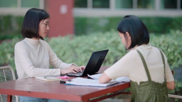 Happy teenagers enjoying outdoor study session under big tree at high school campus searching for creative inspiration and new information to complete difficult homework project well