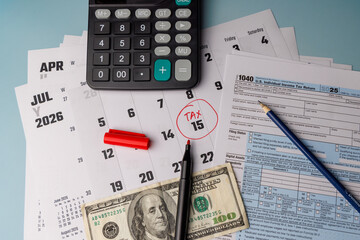 Close up of a hundred dollar bill on IRS Form 1040 in color and a calendar with a red circle on the 15th for financial planning themes.