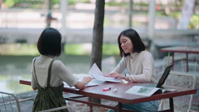 Frustrated female friends looking upset and blaming each other for group work errors at university campus park reflecting toxic relationship and inability to cooperate on difficult thesis