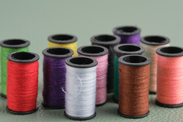 Colorful spools of thread on a green background. Closeup.