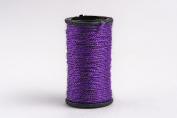 Spool purple thread on white background, closeup.