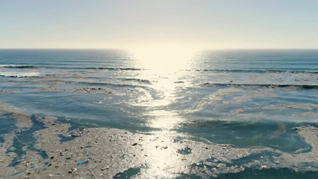 Coastline of polluted shoreline with shimmering sunlight on tainted waters