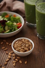 Roasted pumpkin seeds bowl with salad and smoothie in bright healthy lifestyle scene