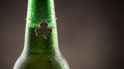 Cold beer bottle with shamrock charm. Green beer bottle covered with water drops, beer party background with copy space for st patrick day celebration, pub toast concept, nightlife mood