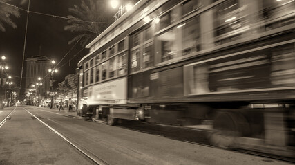 Fototapeta premium Nighttime view of New Orleans red streetcar with city lights in the background