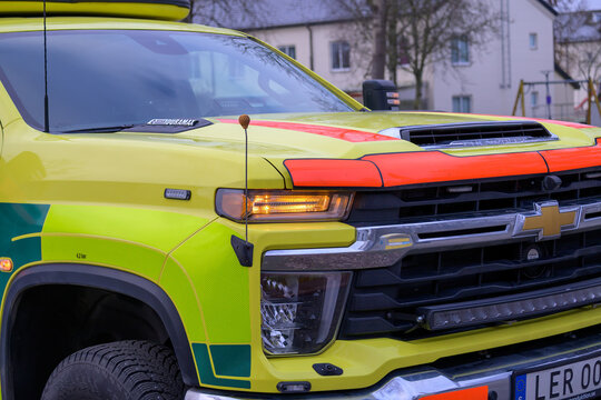 Falkenberg, Sweden - december 24, 2025: An emergency medical services vehicle is parked outside a hospital on a cloudy day. The vehicle is marked with bright colors and has emergency lights on top