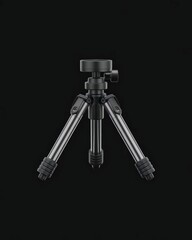 A black tripod for camera or photography equipment on a solid black background