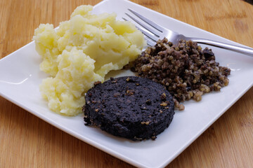 Plate of mashed potato, black pudding and haggis with fork