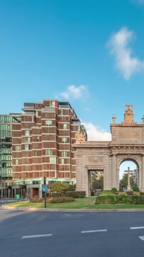 La Porta de la Mar timelapse hyperlapse in Valencia, Spain. Once part of medieval walls, this neoclassical gateway stands on a busy roundabout. A treasured city icon under a bright sky at sunset.