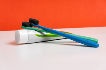 A two toothbrush with toothpaste on red background with copy space, close-up. Dental oral hygiene concept