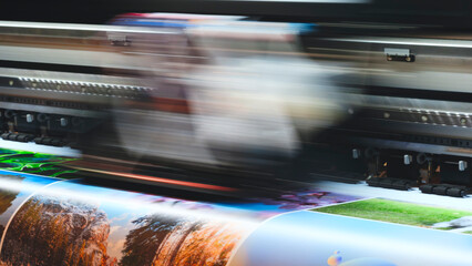 Industrial multi-color printing on paper using a modern digital inkjet RGB printer; the print head blurs as it moves.