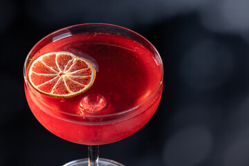 Beautiful cosmopolitan cocktail garnished with a lime wheel with dramatic lighting