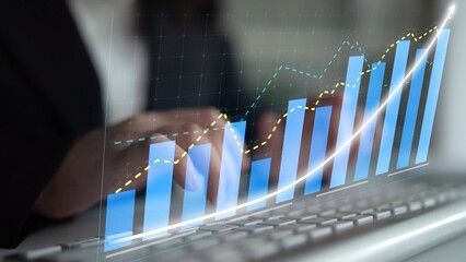 Business professional engages with financial data while typing on a keyboard, featuring dynamic graphs that illustrate growth trends in a modern office setting. Copula