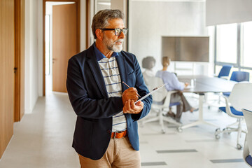 Male accountant holding pen and clipboard thinking business strategies while standing in corporate boardroom