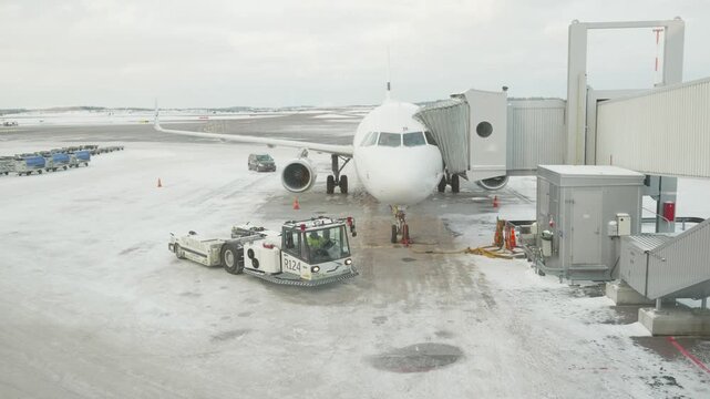 A view of a parked aircraft at a snowy airport gate, showcasing the winter conditions and airport operations.