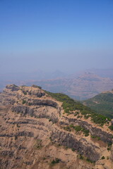 Vertical composition of layered mountain cliffs under clear blue sky