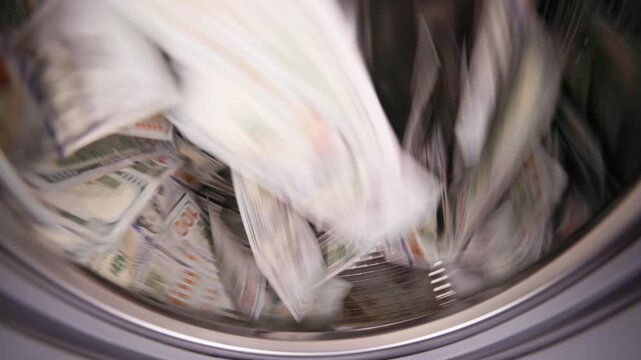 Hundred United States Dollar banknotes are spinning inside a washing machine. Money laundering and fraud concept.