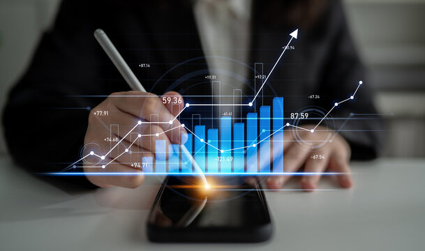 A business professional uses a smartphone to analyze financial data, with vivid growth charts displayed, highlighting technology role in market strategy. Scalp - Powered by Adobe