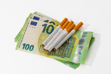 Cigarettes on 100 euro banknotes isolated on white background with clipping path included. Concept of the cost of smoking.