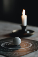 Obraz premium Mystical crystal ball on ancient chart illuminated by a single candle flame in dark room