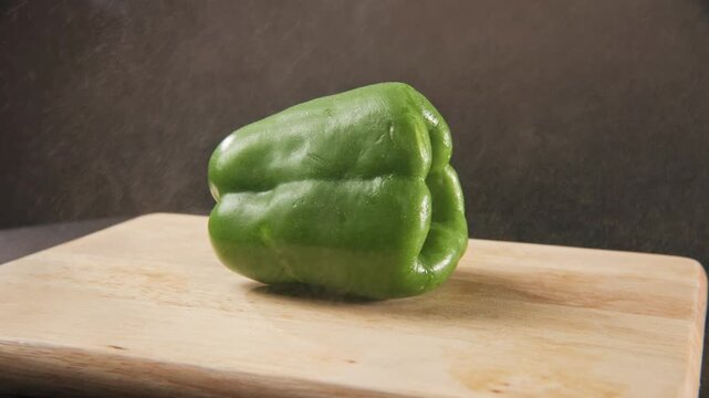 Slo mo slow motion tight close up of fresh wet green bell pepper vegetable and fruit for healthy food and eating in studio setup of healthy-eating colorful veggie is sprayed with bright water