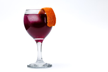 Glass of red wine garnished with orange peel isolated on white background.