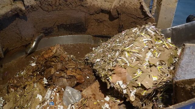 Cardboard boxes are broken down and pulped with water in a large, circular tank. This is part of the paper recycling process at a recycling plant or factory